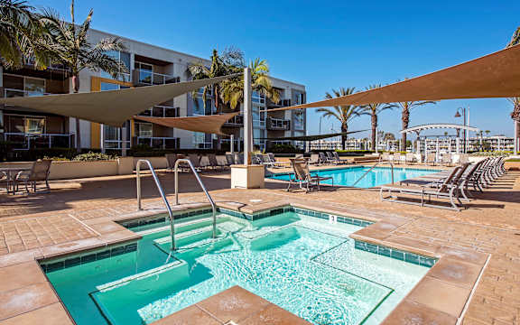 A large outdoor swimming pool with a slide and sun shades.