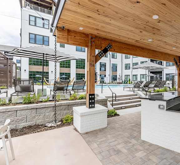 Full outdoor countertop with refrigerators under a modern pergola next to the pool at Novel Cary