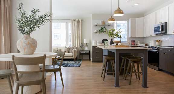 Picturesque open kitchen area with modern island and charcoal color cabinets at Novel Cary