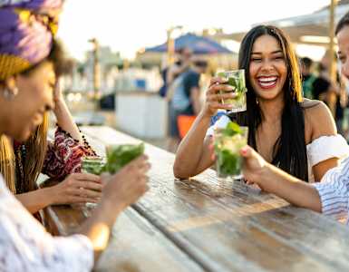 Four people are laughing and enjoying drinks at Brea Grove Residences Apartments, Brea, California