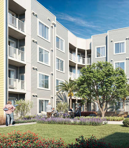 A modern apartment complex with balconies and a landscaped garden in front at The Stillwaters 62+ Apartment Homes, Apopka, FL, 32712