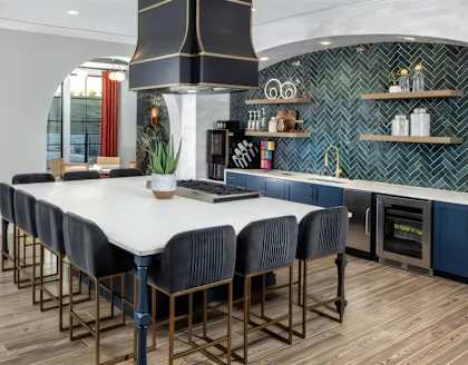 a kitchen with a large white table and blue chairs