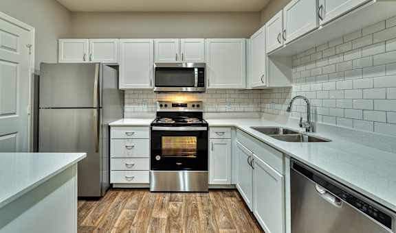 a kitchen with white cabinets and stainless steel appliances