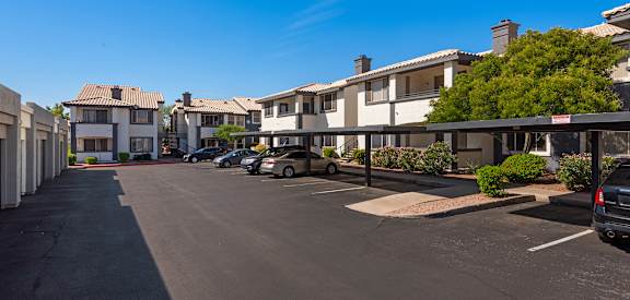 a parking lot with cars parked in front of apartment buildings