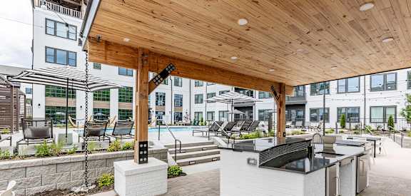 Full outdoor countertop with refrigerators under a modern pergola next to the pool at Novel Cary
