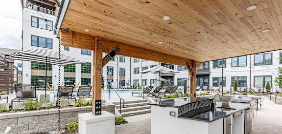Full outdoor countertop with refrigerators under a modern pergola next to the pool at Novel Cary