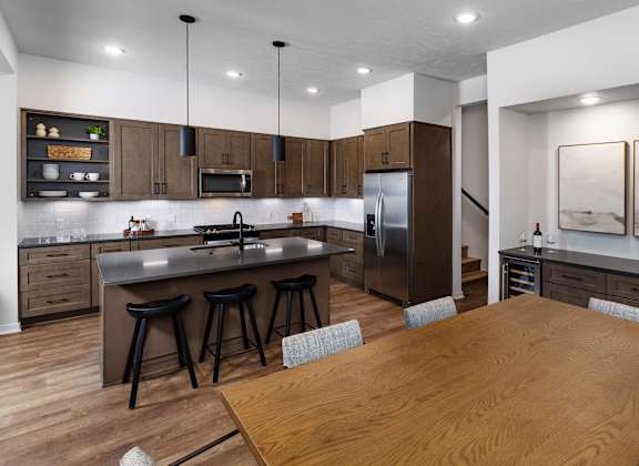 A modern kitchen with a wooden table and bar stools.