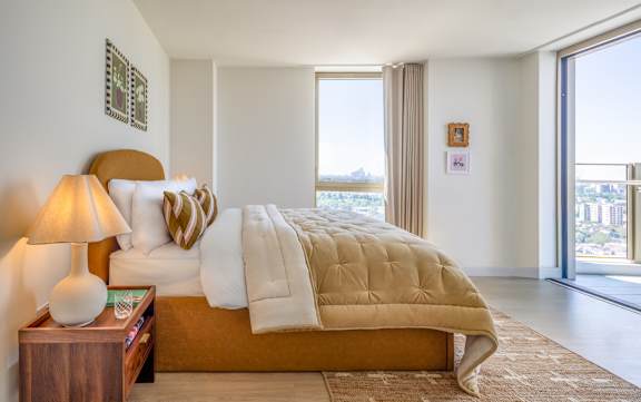 A bedroom with a large bed and a lamp on a side table.