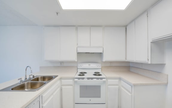 a kitchen with white cabinets and white appliances and a sink at Flamingo Garden Senior Apts, El Monte, CA