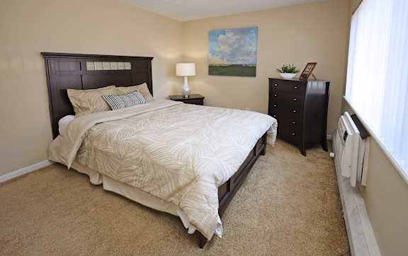 A bedroom with a large bed and a painting on the wall.
