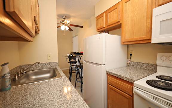 A kitchen with a white refrigerator, white stove, and a white sink.