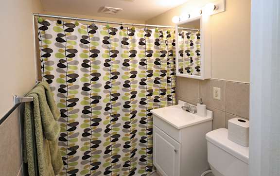 A bathroom with a shower curtain, toilet, and sink.
