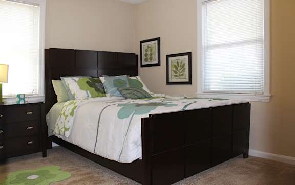 A bedroom with a bed, nightstand, and two framed pictures on the wall.