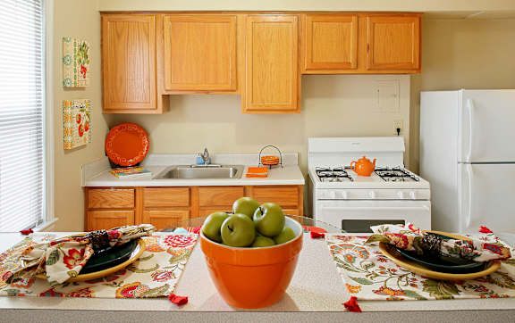 A kitchen with a bowl of green apples on the counter.