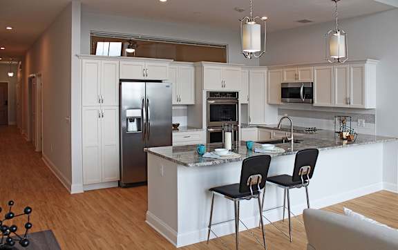 A kitchen with a refrigerator, oven, and sink.