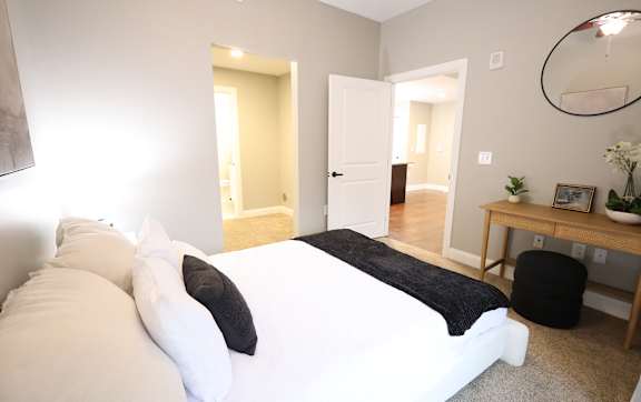 A bedroom with a white bed and a black and white blanket.