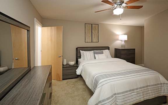 A bedroom with a bed, nightstand, and a ceiling fan.