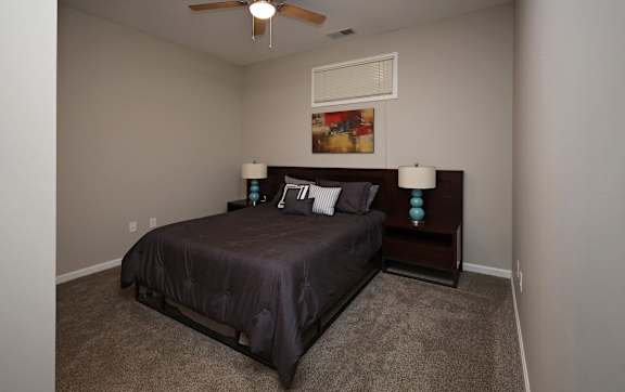 A bedroom with a bed, two lamps, and a painting on the wall.