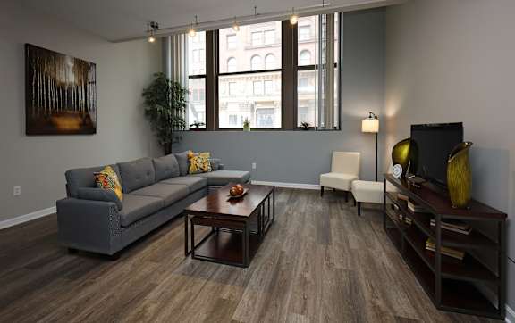 A living room with a grey couch, a coffee table, a chair, and a painting on the wall.