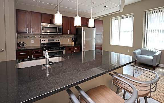 A kitchen with a black granite countertop and stainless steel appliances.