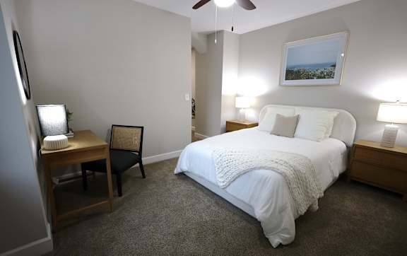 A bedroom with a large bed and a ceiling fan.