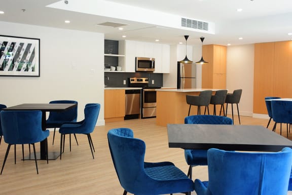 a dining room with blue chairs and tables and a kitchen