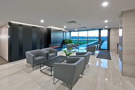A modern waiting area with grey chairs and a view of the outside.