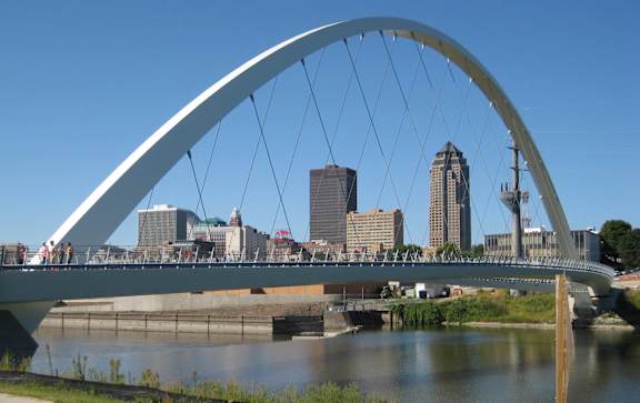 A bridge over a river with a city skyline in the background.