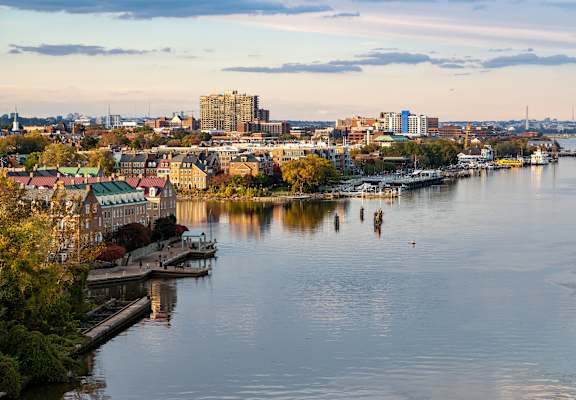 A cityscape with buildings, boats, and people on the water.