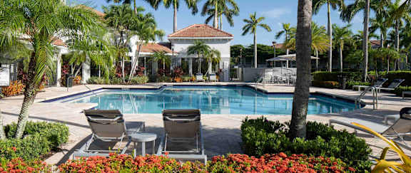 A large building with a pool in the foreground and lights on.