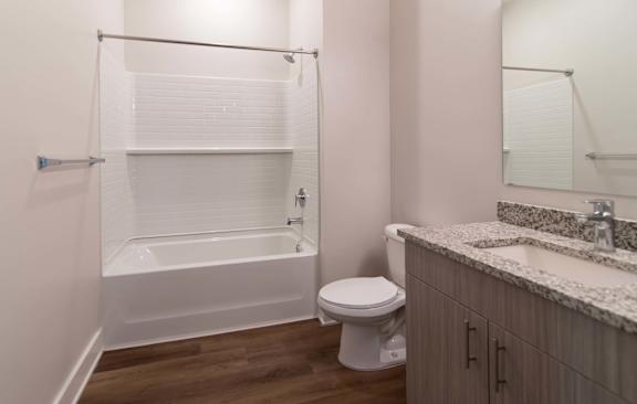 A white bathtub is in a bathroom with a toilet and sink.