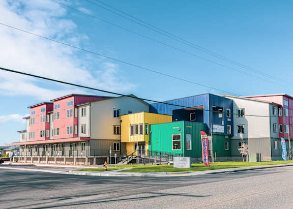A row of colorful buildings are lined up next to a street.
