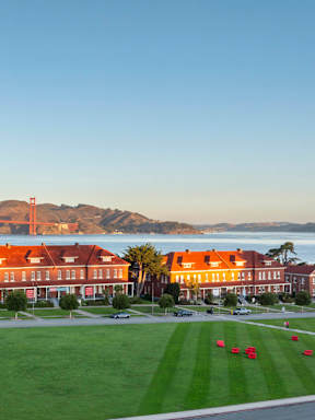 A large building with a red roof is surrounded by a green lawn.