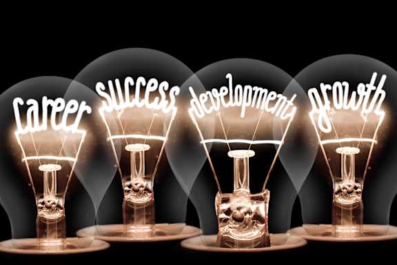 Four light bulbs with the words career, success, development, and growth inside them.