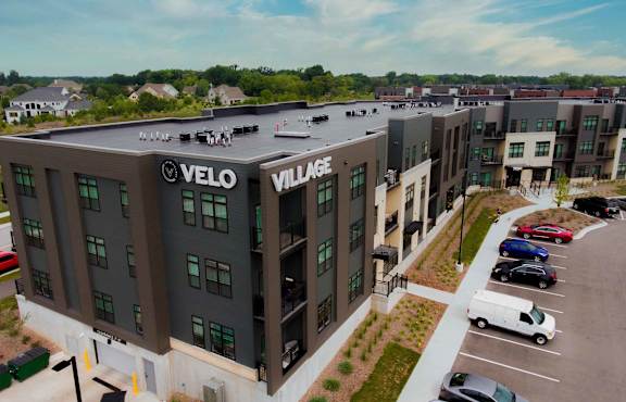 A parking lot in front of a building with the word "Velo" on it.