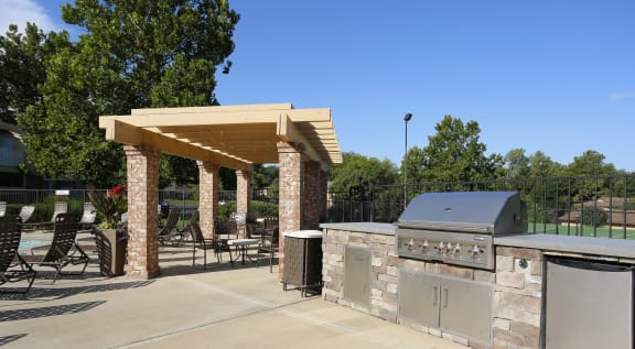 a patio with a barbecue grill and a table with chairs at Lodge of Overland Park Apartments, Overland Park , 66212