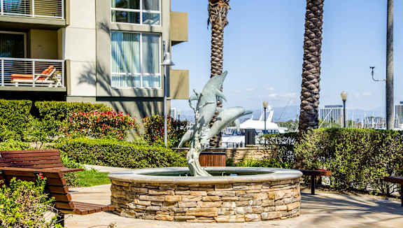 A statue of a dolphin is in the middle of a fountain in a courtyard.