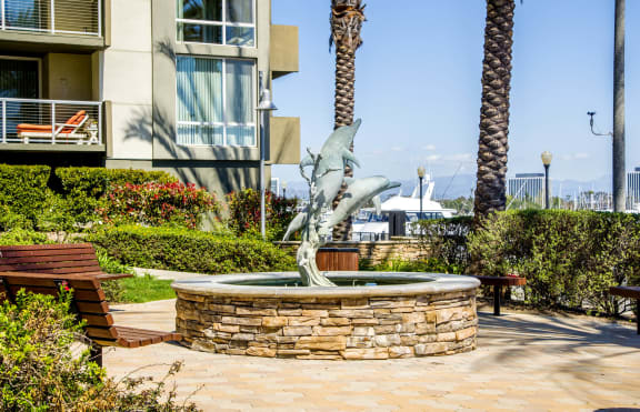 a fountain with a dolphin statue in front of a building at Marina Harbor, Marina del Rey, California