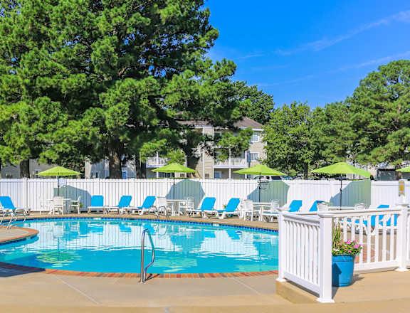 A pool surrounded by white chairs and umbrellas.