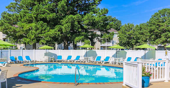 A pool surrounded by white chairs and umbrellas.