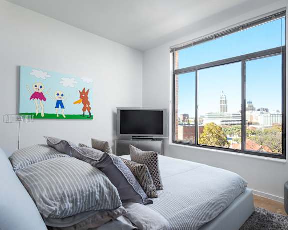 A bedroom with a large bed and a painting of three people on the wall.