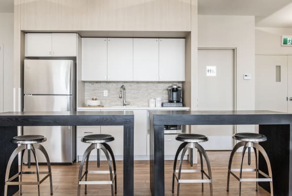 a kitchen with white cabinets and a counter with three stools