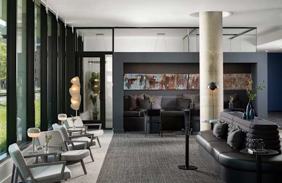A modern living room with a black couch and grey chairs.