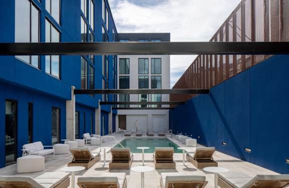 A modern building with a pool and lounge chairs.