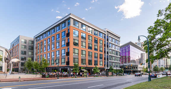 A modern building with a glass facade is situated on a street corner.