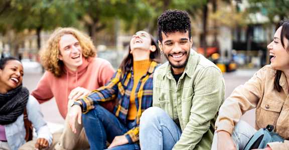 A group of friends sitting on a bench outdoors.