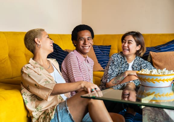 a group of people sitting on a couch with a bowl of popcorn