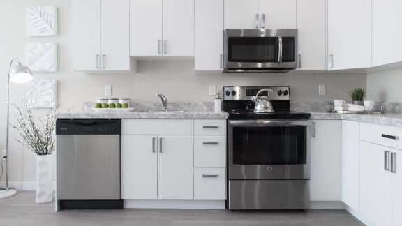 a white kitchen with stainless steel appliances and white cabinets