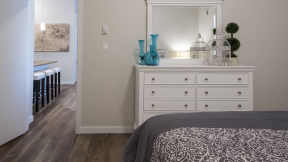 a bedroom with a white dresser with a mirror and a bed