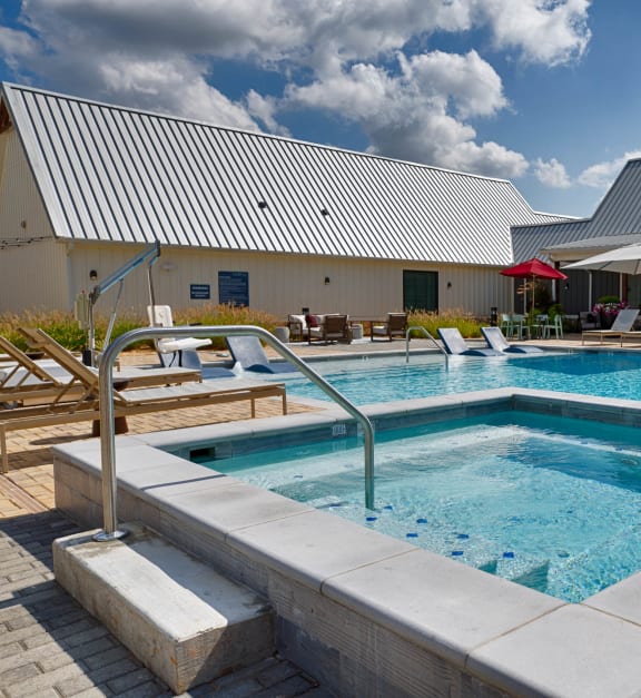 a swimming pool with chairs and a building in the background at Farmhaus Apartments, Alabama, 35757
